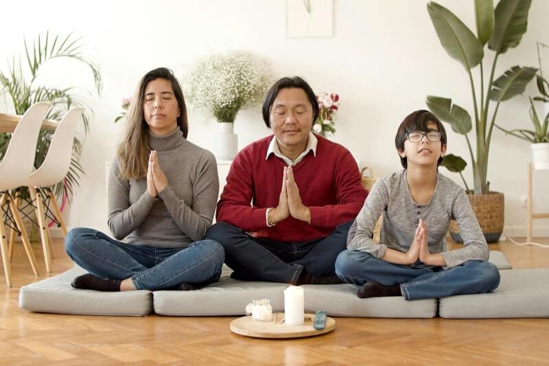 A Family Sitting on Cushions on the Floor while Meditating Together